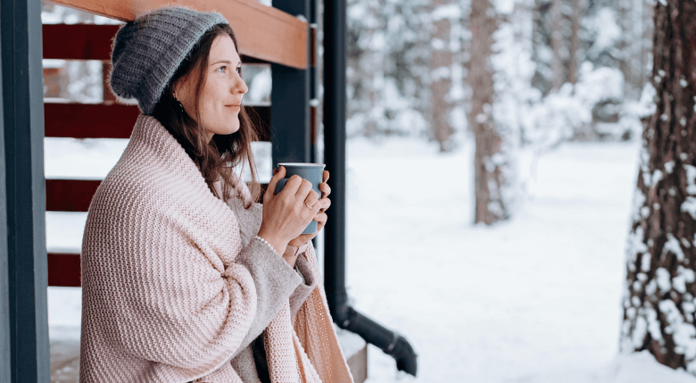 femeie care bea ceai într-un decor de iarnă