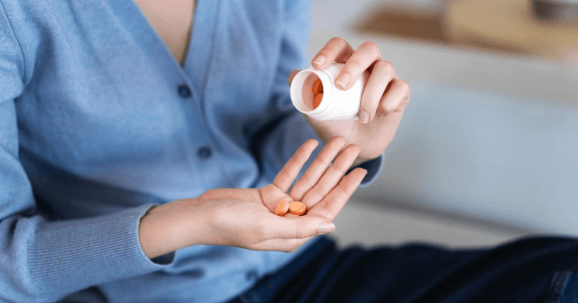 Care sunt cele mai bune suplimente pentru colesterol (femeie care ia pastile, suplimente pentur colesterol, pulover albastru)